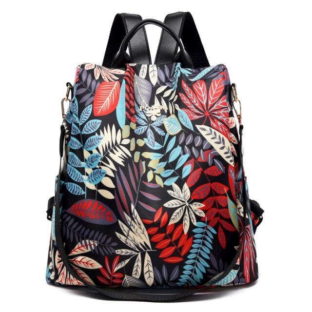 Sac à dos floral coloré avec motifs de feuilles rouges, bleues et blanches, design moderne et élégant, idéal pour la mode et le voyage.