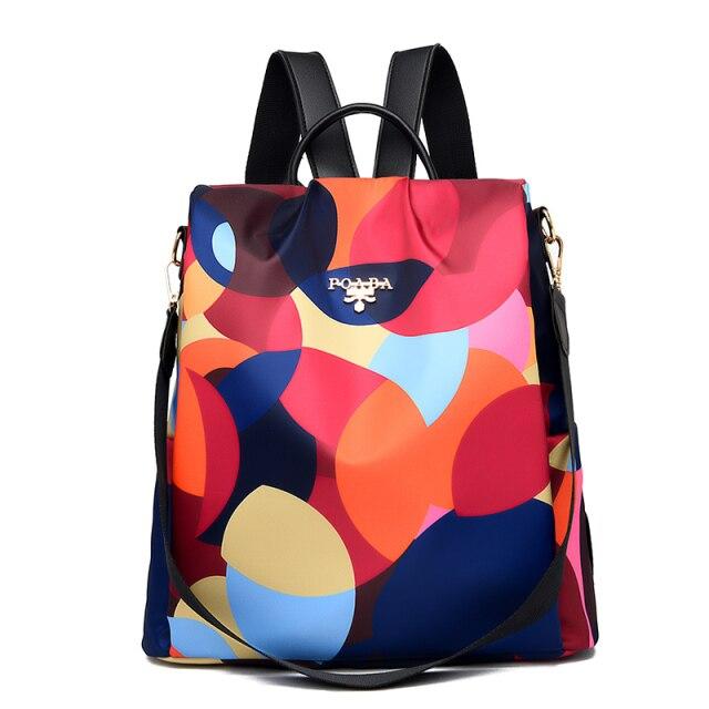 Sac à dos multicolore en tissu imperméable avec motifs géométriques, bretelles ajustables et logo sur le devant. Accessoire mode tendance et pratique.