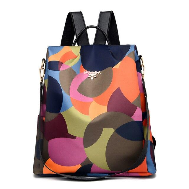 Sac à dos multicolore en toile avec motifs géométriques, bretelles noires ajustables et fermeture éclair. Accessoire mode tendance et pratique.