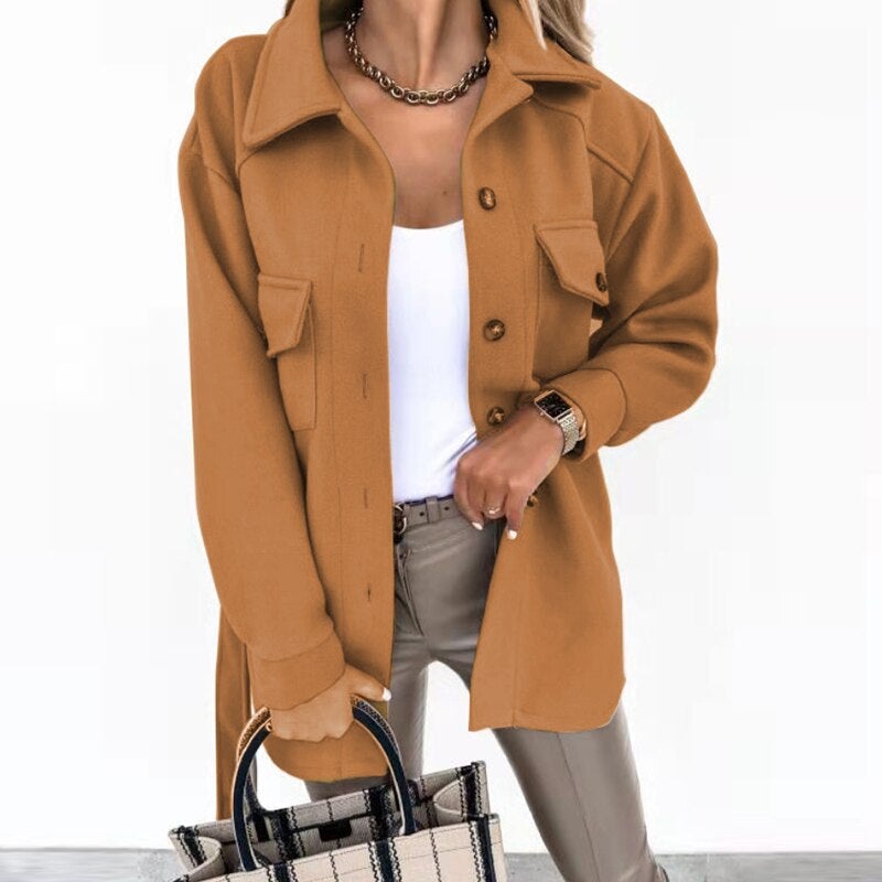 Femme portant une surchemise marron avec boutons, tenue chic avec pantalon beige et sac à main à carreaux, style automne-hiver tendance.