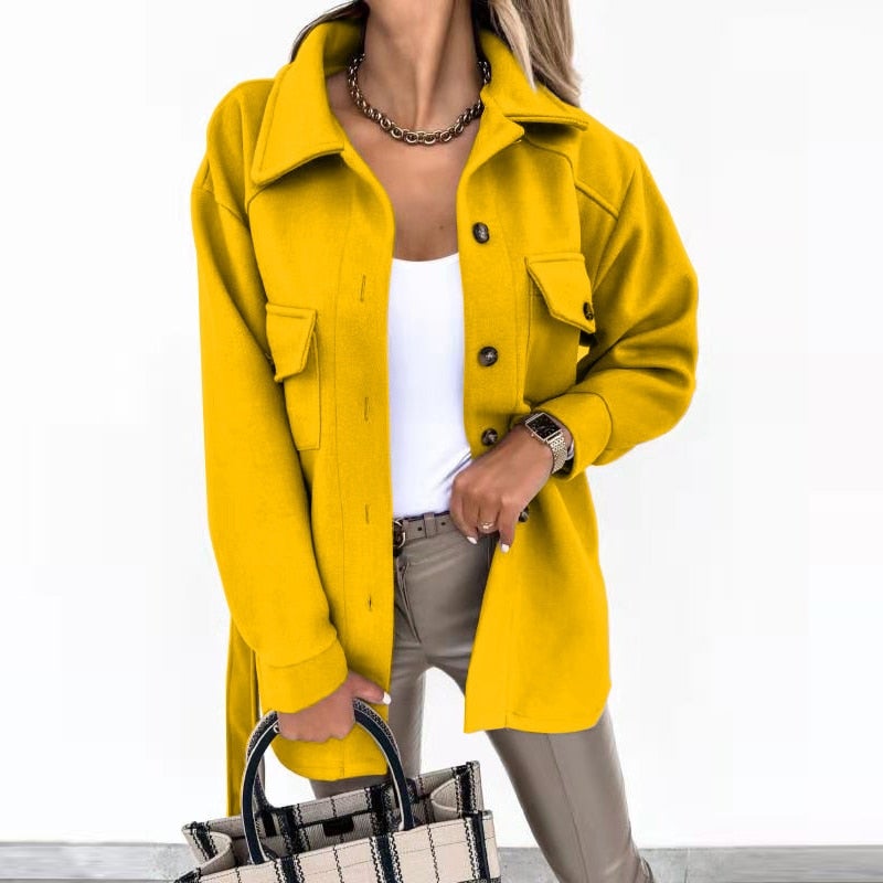 Femme portant une veste jaune tendance, chemise blanche, pantalon beige, tenant un sac à main élégant. Mode automne, style chic et moderne.