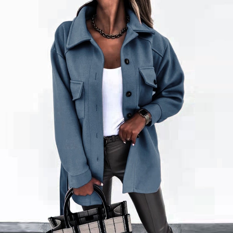 Femme portant une surchemise bleue élégante, chemise blanche, pantalon en cuir noir, collier chaîne, tenant un sac à main moderne. Mode automne chic.