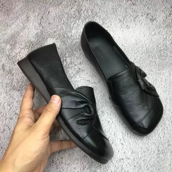Chaussures en cuir noir pour femme avec nœud décoratif, semelle plate, confortables et élégantes, parfaites pour un style décontracté ou professionnel.