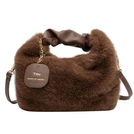 Sac à main en fausse fourrure marron avec bandoulière en cuir, étiquette dorée "You Deserve Better", design élégant et moderne, mode automne-hiver.