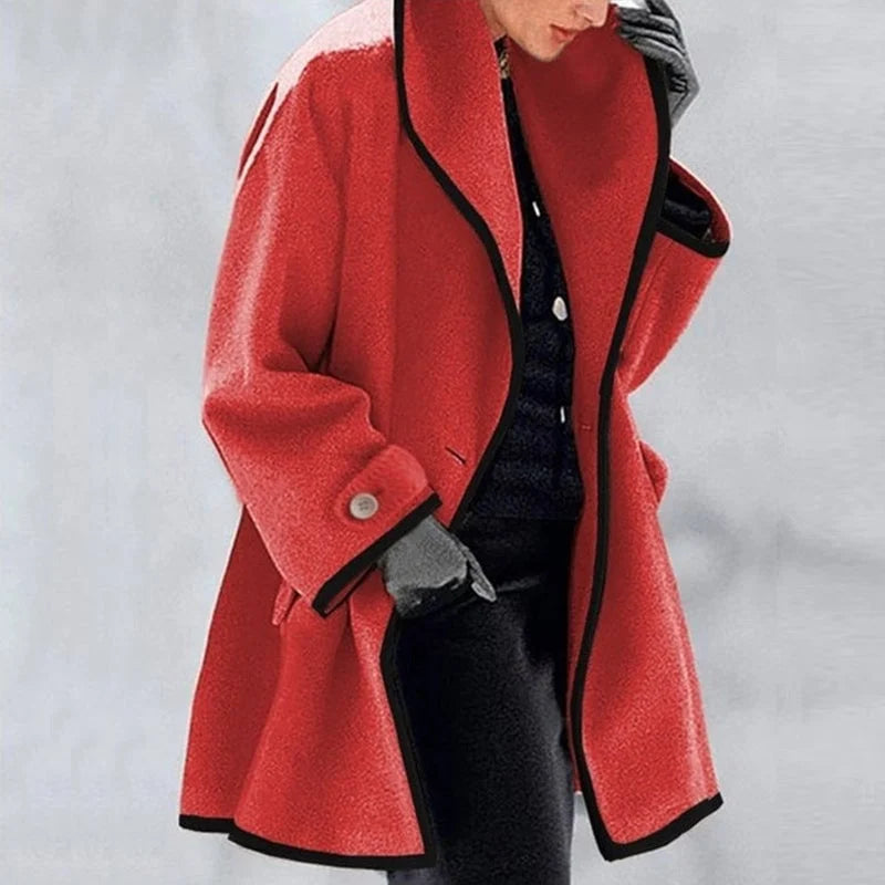 Manteau rouge élégant avec bordures noires, porté par une personne en tenue hivernale. Mode automne-hiver, style chic et moderne.