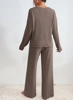 Femme portant un ensemble lounge en tricot marron, pull à manches longues et pantalon large, sur fond blanc. Mode confortable et élégante.