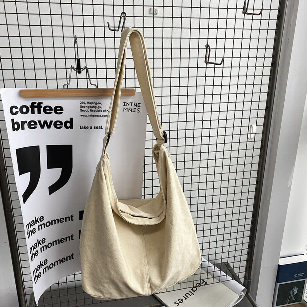 Sac à main en toile beige suspendu devant un fond de grille métallique, avec affiches modernes en noir et blanc. Accessoire mode tendance et minimaliste.