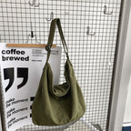 Sac à main vert olive suspendu sur un grillage, design moderne et minimaliste. Accessoire mode tendance, idéal pour un look urbain chic.
