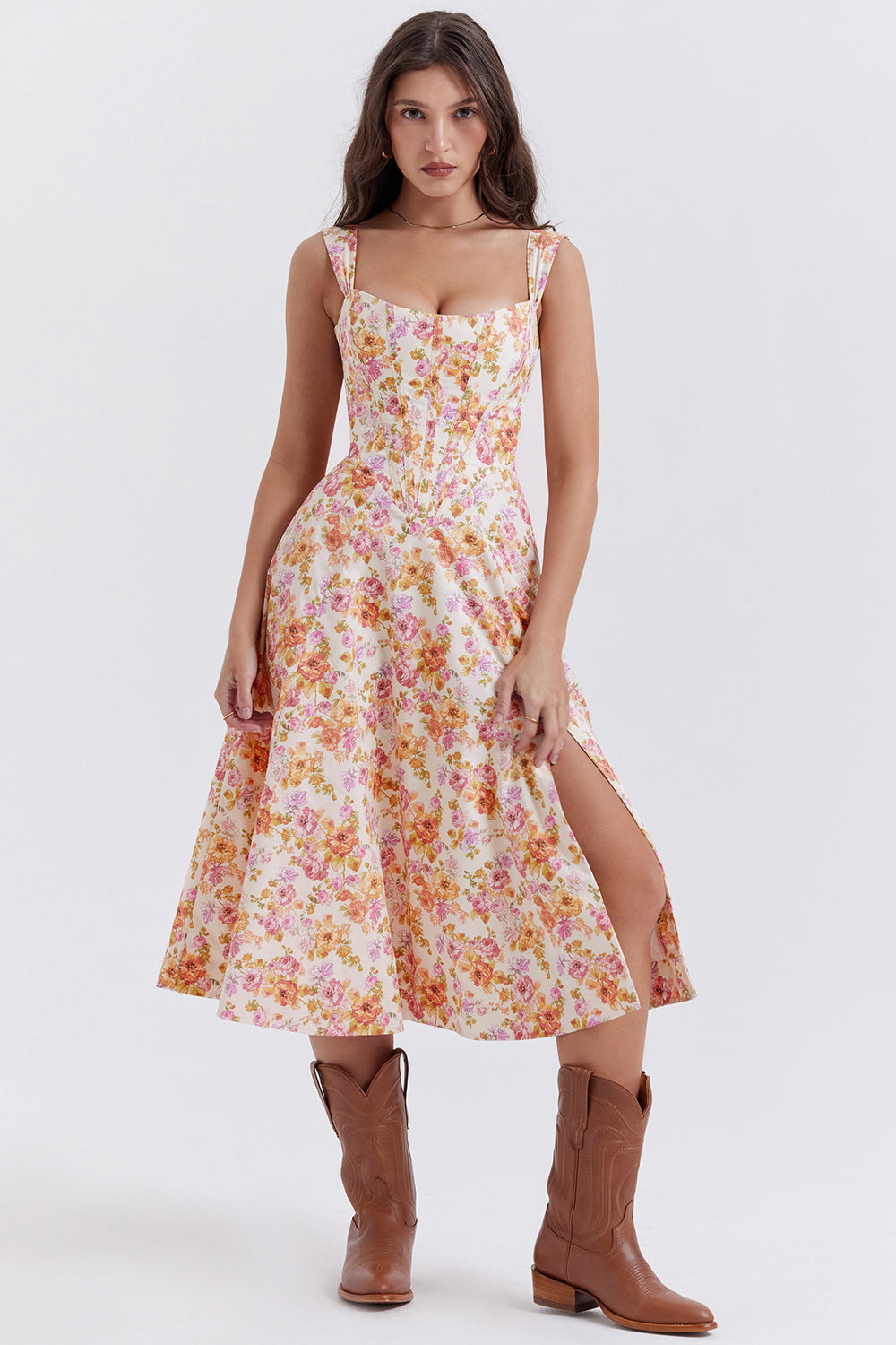 Robe longue à fleurs roses et jaunes, fendue, portée par une femme avec bottes marron. Mode féminine, style bohème, tendance été.