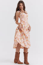 Jeune femme portant une robe à fleurs pastel et des bottes marron, posant debout. Mode féminine, style champêtre, élégance décontractée.