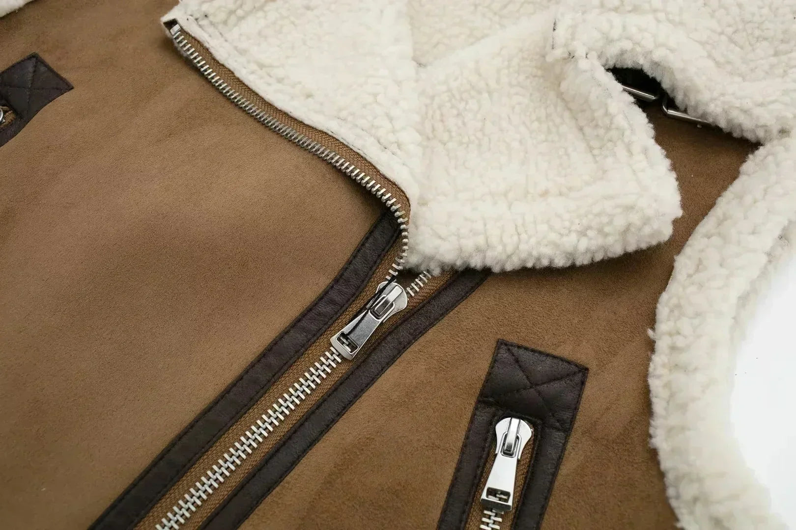 Veste aviateur en cuir marron avec doublure en laine blanche, fermetures éclair argentées et détails en cuir noir. Mode hiver, style vintage.