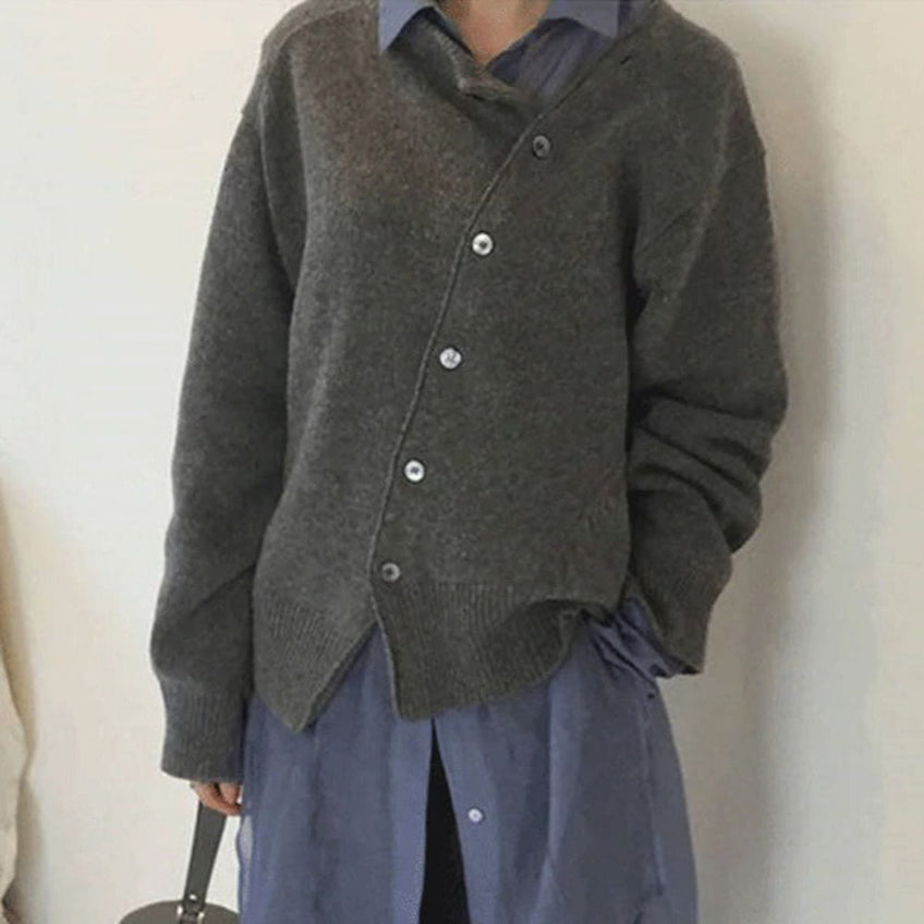 Personne portant un cardigan gris asymétrique sur une chemise bleue, style décontracté et moderne, mode automne-hiver, vêtements en laine.