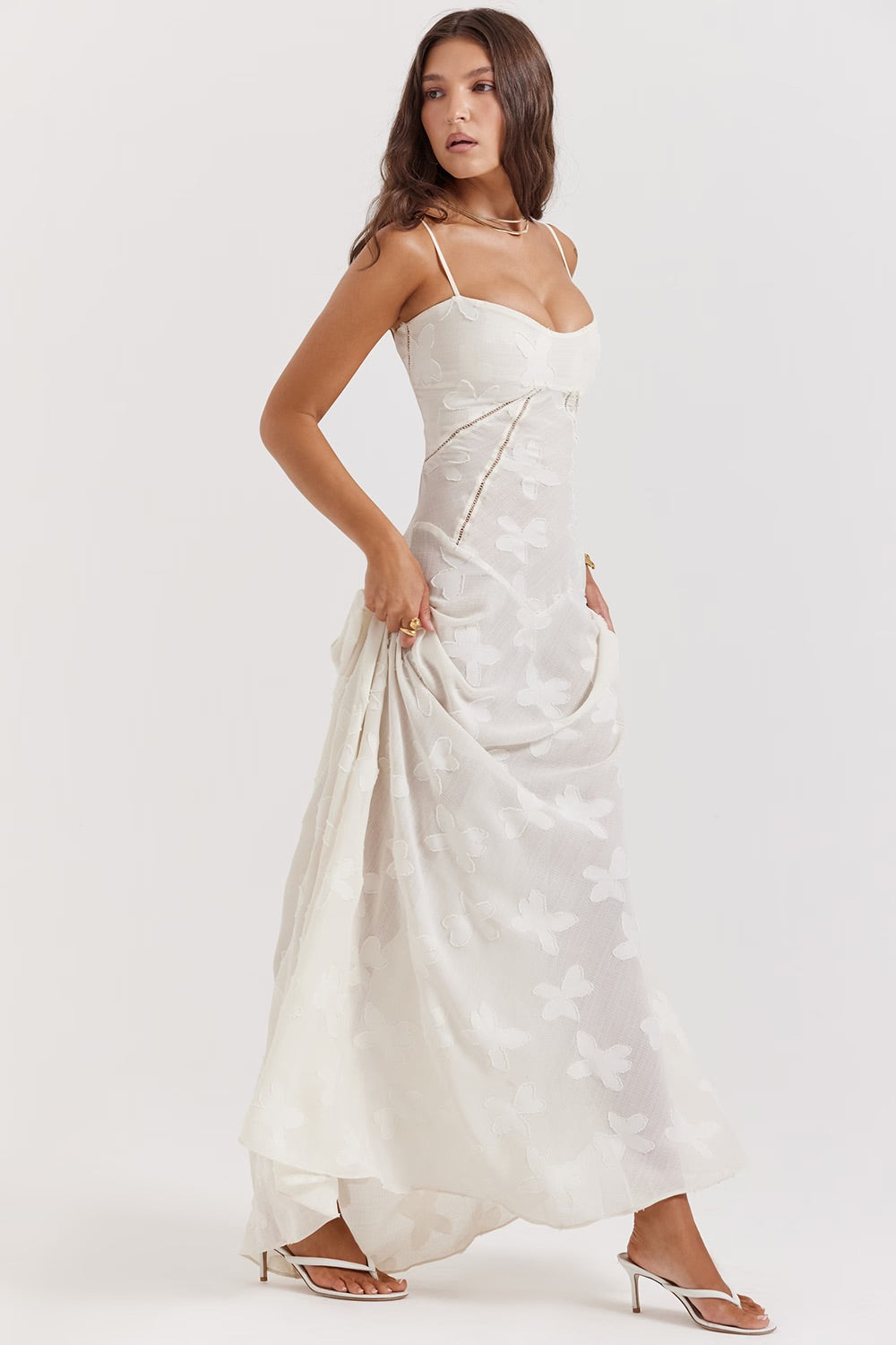 Robe longue blanche élégante avec motifs floraux, bretelles fines et coupe ajustée, portée par une femme. Mode féminine, tenue de soirée chic.