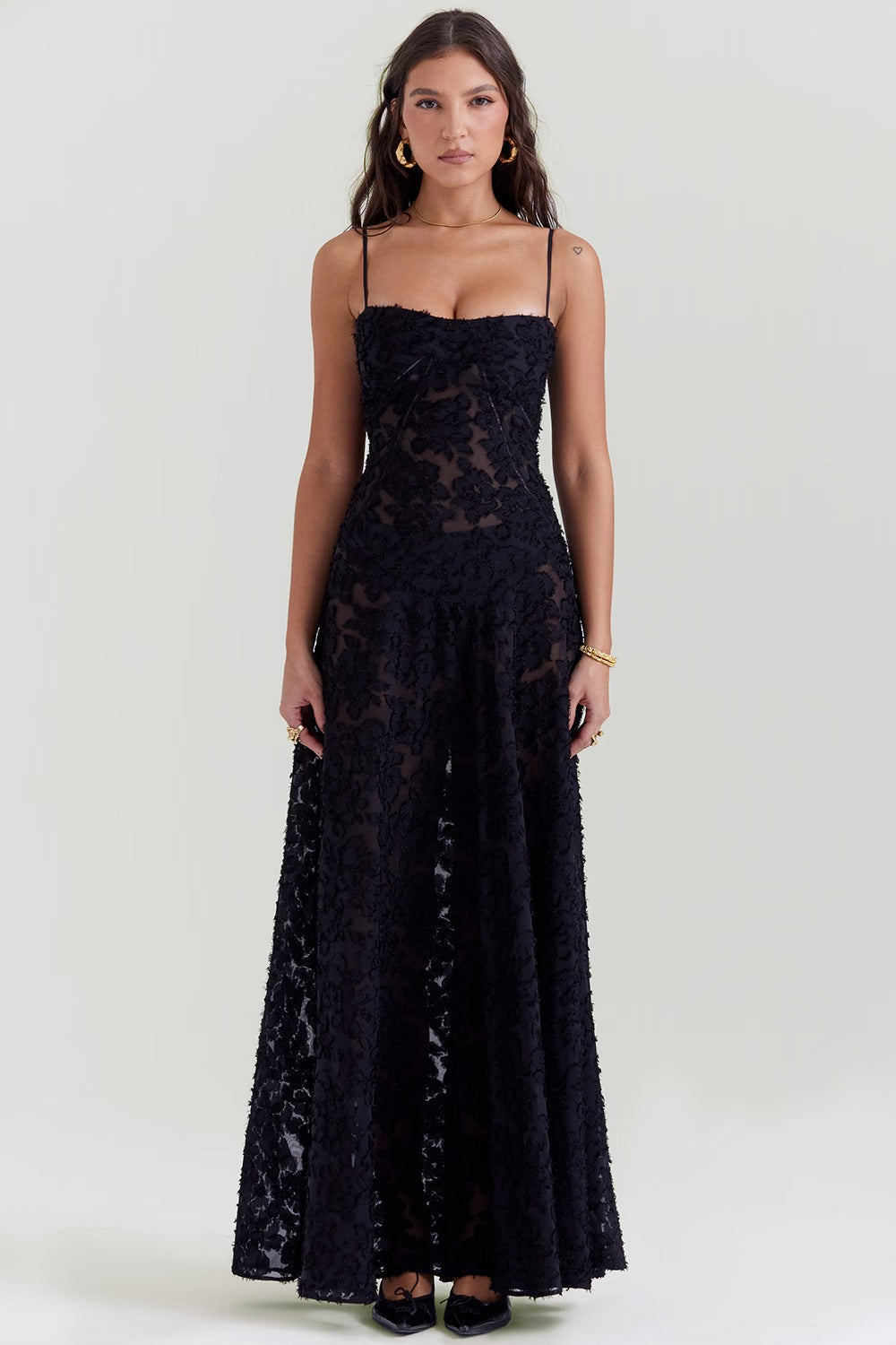 Robe longue noire en dentelle florale, bretelles fines, portée par une femme. Élégante tenue de soirée, mode féminine chic et tendance.