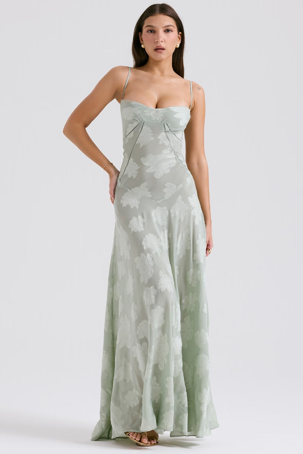 Robe longue verte à motifs floraux, bretelles fines, portée par une femme. Mode élégante, tenue de soirée, style chic et tendance.
