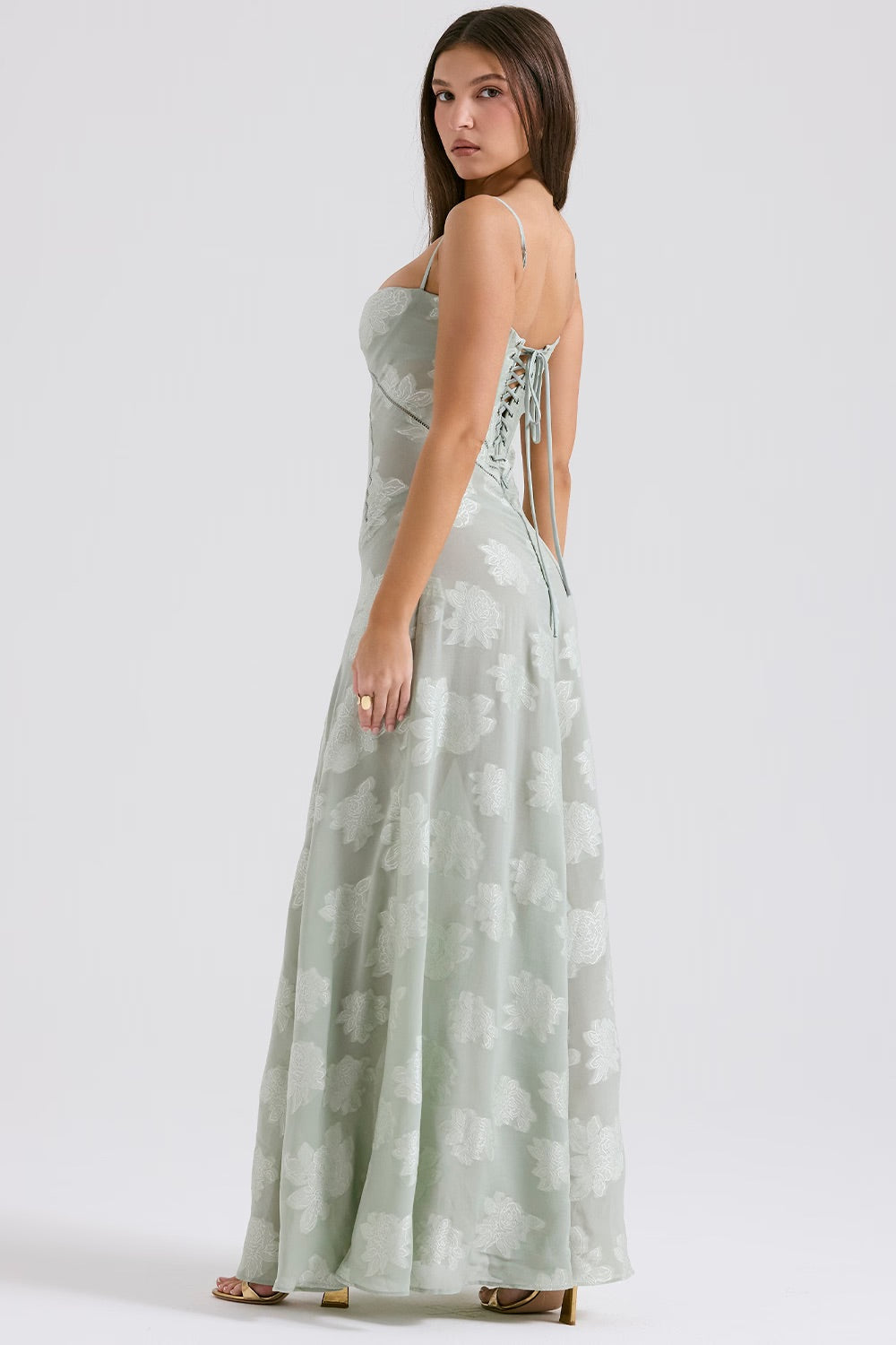 Robe longue verte à motifs floraux, dos lacé, portée par une femme. Mode élégante, tenue de soirée, style chic et tendance.