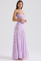 Femme en robe longue lilas à bretelles fines, motif floral, posant de profil. Mode élégante, tenue de soirée, style chic et tendance.