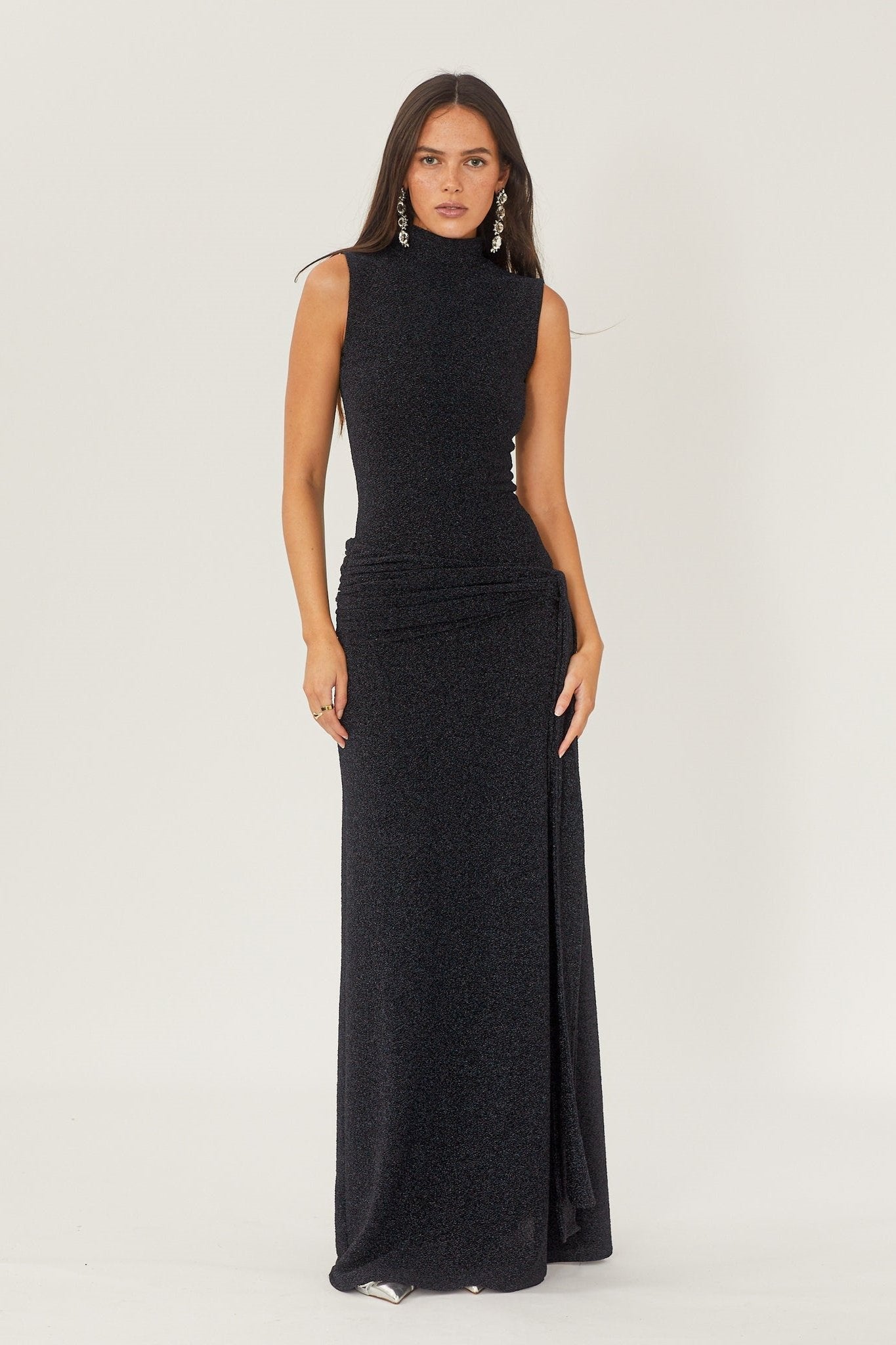 Robe de soirée longue noire élégante, sans manches, avec col montant, portée par une femme. Mode féminine chic, tenue de gala sophistiquée.