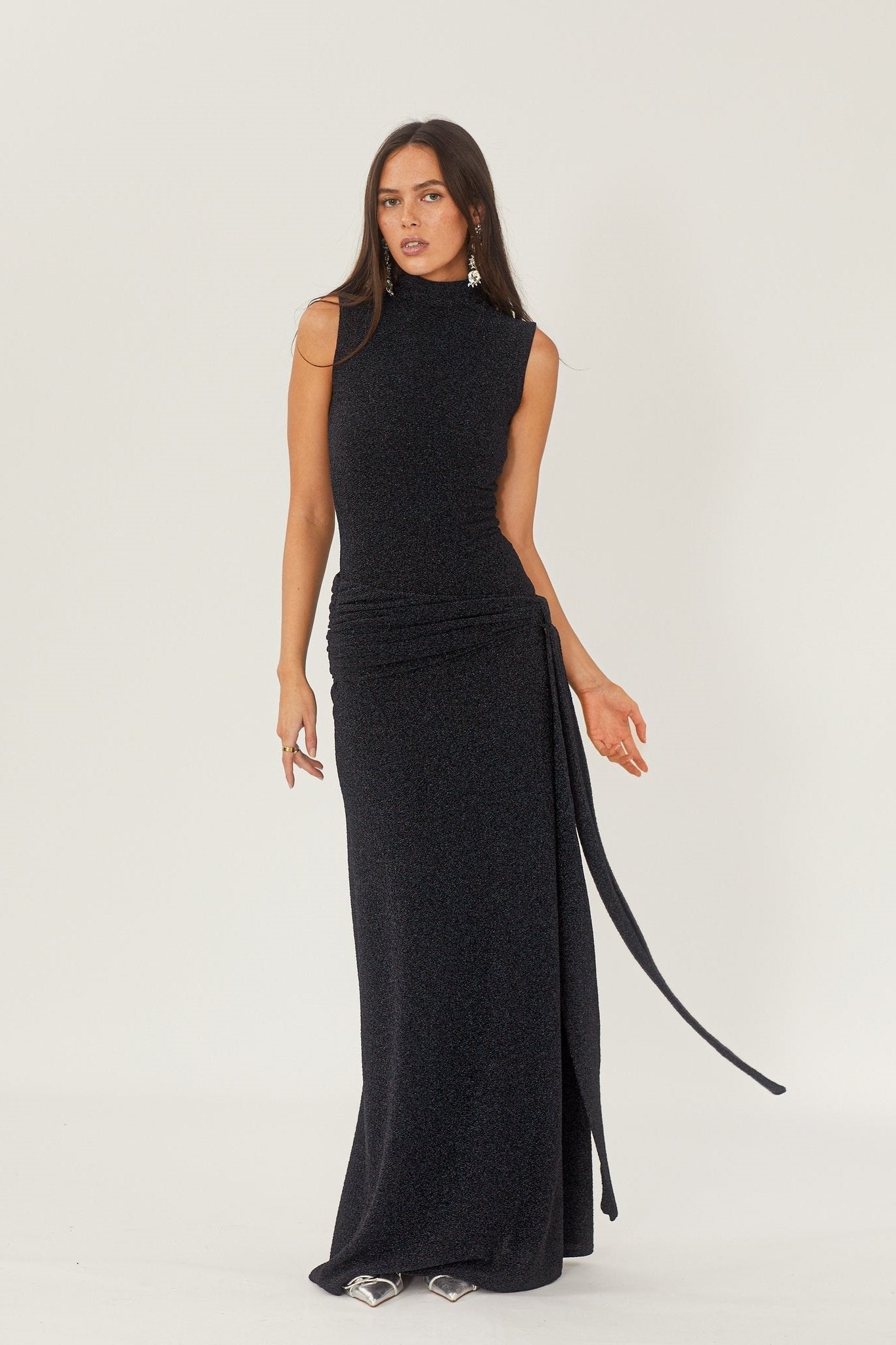 Robe longue noire élégante avec col montant, sans manches, portée par une femme. Style chic et moderne, idéal pour soirées et événements formels.