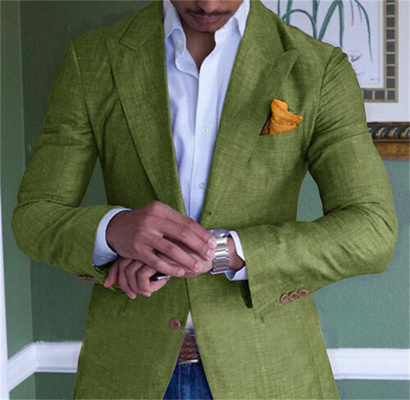 Homme en costume vert élégant, chemise blanche, ajustant sa montre-bracelet argentée. Poche avec mouchoir orange. Mode masculine chic.