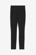 Pantalon noir à rayures verticales blanches, coupe ajustée, style élégant et moderne, idéal pour tenues professionnelles ou occasions formelles.
