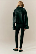 Femme de dos portant une veste en cuir noir oversize, leggings noirs côtelés et ballerines noires. Mode automne, style urbain chic.