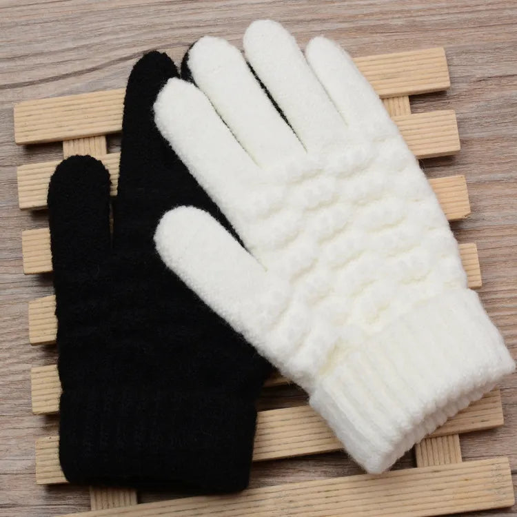 Deux gants en laine, un noir et un blanc, posés sur une surface en bois. Accessoires d'hiver, confortables et chauds, parfaits pour le froid.