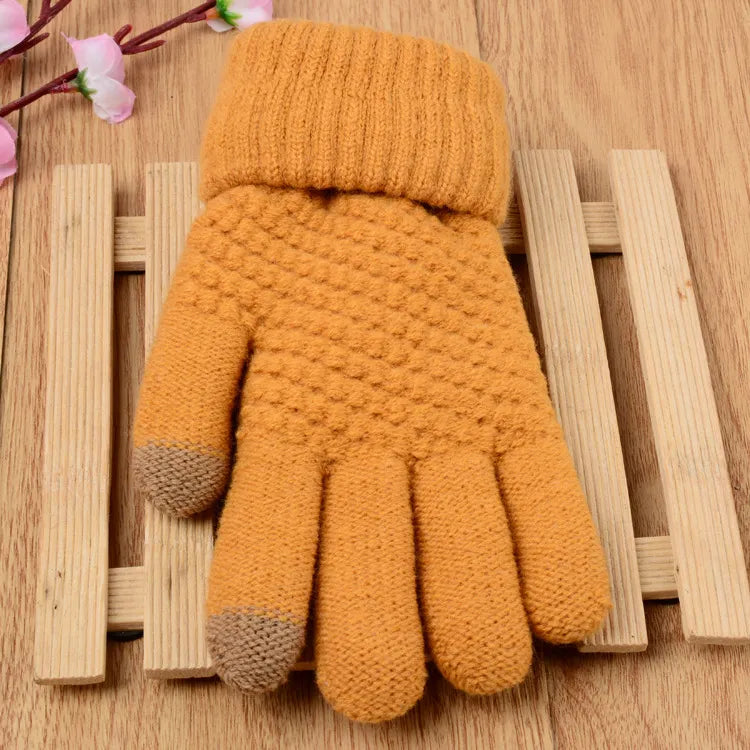 Gant en laine jaune moutarde avec bouts de doigts marron, posé sur une surface en bois. Accessoire d'hiver chaud et élégant.