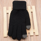 Gant noir tactile en laine sur fond de bois, idéal pour l'hiver. Accessoire chaud et pratique pour utiliser les écrans tactiles par temps froid.