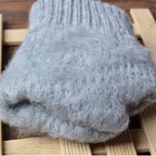 Gants en laine grise moelleuse posés sur une surface en bois, parfaits pour l'hiver. Accessoire chaud, doux et confortable pour le froid.