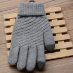 Gant en laine gris avec motif torsadé, posé sur un fond en bois. Accessoire d'hiver chaud et élégant, idéal pour le froid.