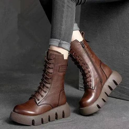 Bottes en cuir marron à lacets avec semelles épaisses, portées avec un jean gris. Chaussures tendance pour l'automne et l'hiver.