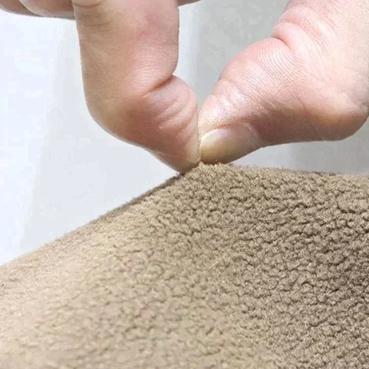 Main tenant un tissu polaire beige, texture douce et moelleuse, gros plan. Matériau chaud idéal pour vêtements d'hiver et couvertures.