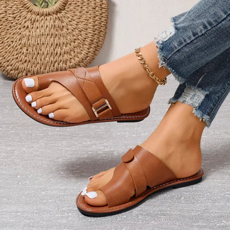 Sandales en cuir marron pour femme avec boucle, portées avec un jean déchiré. Chaussures d'été élégantes et confortables, tendance mode féminine.