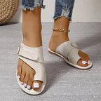 Sandales blanches en cuir pour femme avec boucle, portées avec un jean déchiré. Chaussures d'été élégantes et confortables, tendance mode féminine.