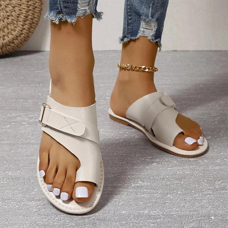 Sandales blanches en cuir pour femme avec boucle, portées avec un jean déchiré. Chaussures d'été élégantes et confortables, tendance mode féminine.