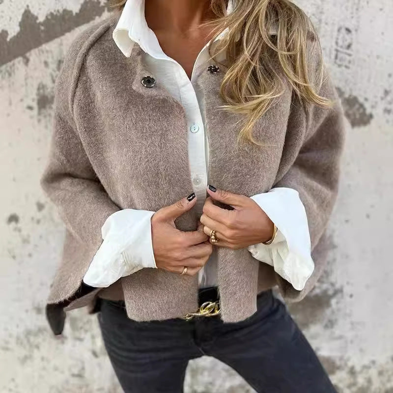 Femme portant un manteau en laine beige sur une chemise blanche, avec un jean noir. Mode automne, style chic et décontracté, tendance vestimentaire.