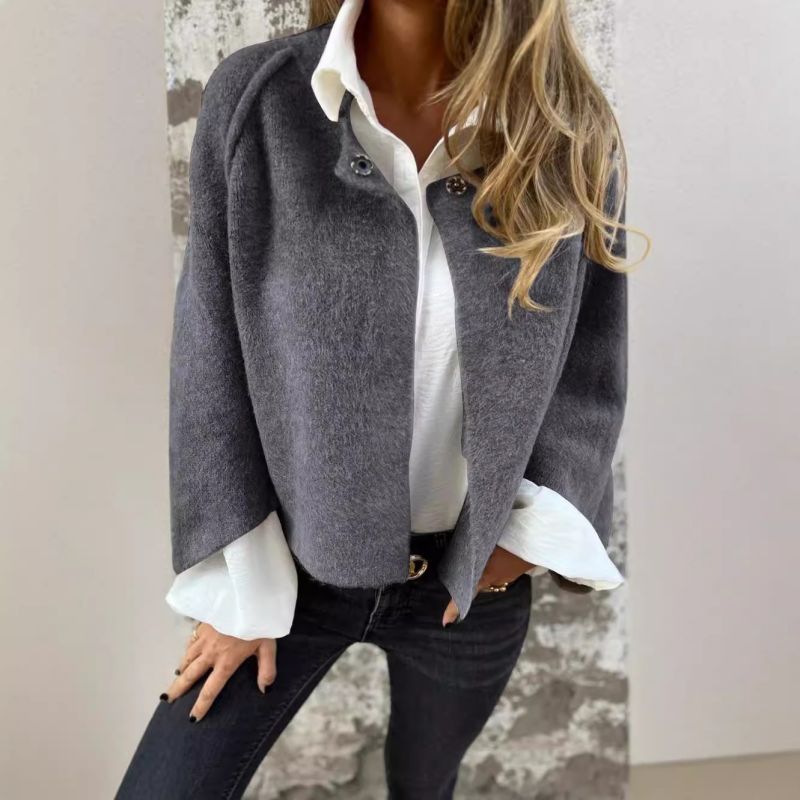 Femme portant une veste grise élégante sur chemise blanche, jeans noir ajusté. Mode automne chic, tenue décontractée tendance, style moderne.