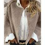 Femme portant un manteau en laine beige sur une chemise blanche, accessoirisée d'une ceinture dorée. Mode automne-hiver élégante et chic.