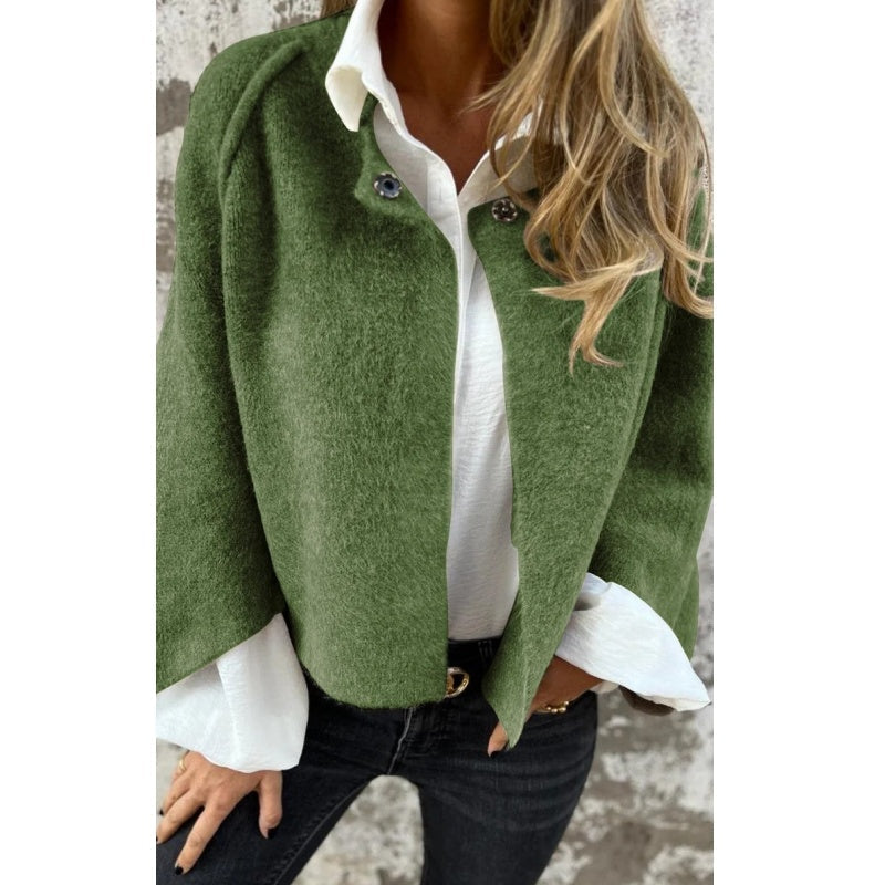 Femme portant un manteau vert en laine, chemise blanche et jeans noirs. Mode automne, style élégant et décontracté, tendance vestimentaire.