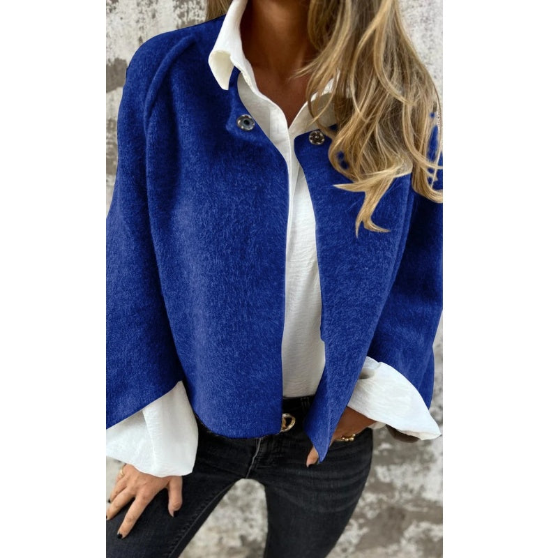 Femme portant une veste bleue élégante sur une chemise blanche, avec un jean noir. Mode automne, style chic et décontracté.