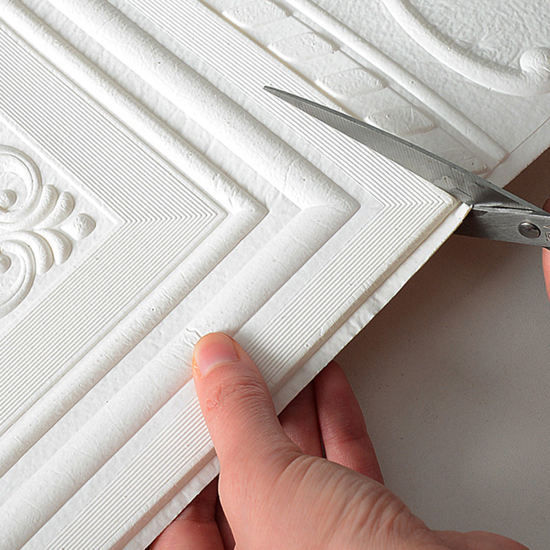 Découpe de papier peint texturé blanc avec des ciseaux, motif géométrique et ornemental, décoration murale intérieure, bricolage maison.