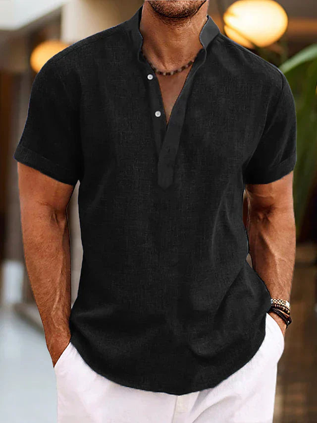Homme portant une chemise noire en lin à col mao, manches courtes, avec boutons, style décontracté, mode masculine élégante, intérieur moderne.