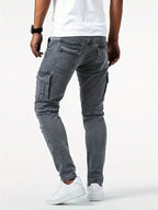 Jeans cargo gris pour homme, coupe ajustée, poches latérales, porté avec des baskets blanches et un t-shirt blanc, style décontracté moderne.