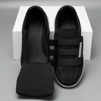 Chaussures orthopédiques noires avec fermeture velcro, semelle intérieure amovible, posées sur une boîte blanche. Confort et soutien pour pieds sensibles.