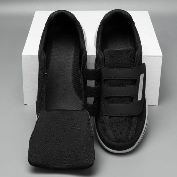 Chaussures orthopédiques noires avec fermeture velcro, semelle intérieure amovible, posées sur une boîte blanche. Confort et soutien pour pieds sensibles.