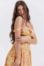 Femme en robe jaune à fleurs, cheveux longs et bruns, pose élégante. Mode féminine, style estival, tendance robe fleurie.