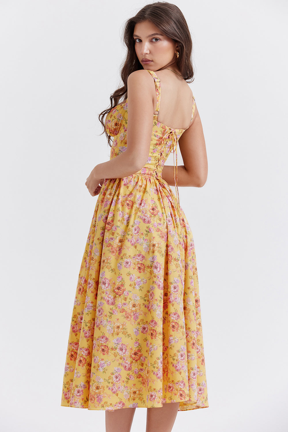 Robe longue jaune à fleurs, dos lacé, portée par une femme. Mode féminine, style estival, tenue élégante et décontractée.