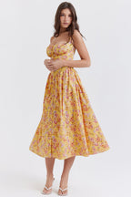 Robe longue jaune à fleurs portée par une femme, style été, bretelles fines, coupe évasée. Mode féminine, tendance estivale, élégance décontractée.
