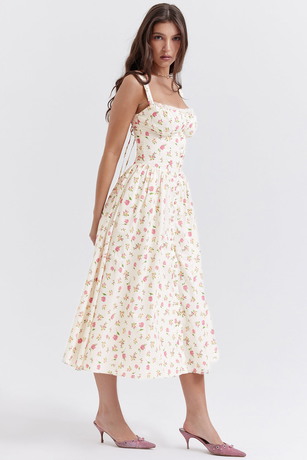 Robe longue à fleurs blanches et roses, bretelles fines, portée par une femme. Style estival élégant, mode féminine tendance, chaussures roses.